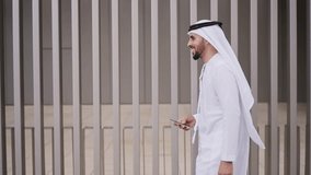 Handsome businessman with the traditional emirates white outfit working outdoor in Dubai city. Concept about middle eastern cultures and business - Powered by Shutterstock - Get 15% off with code: PIKWIZARD15