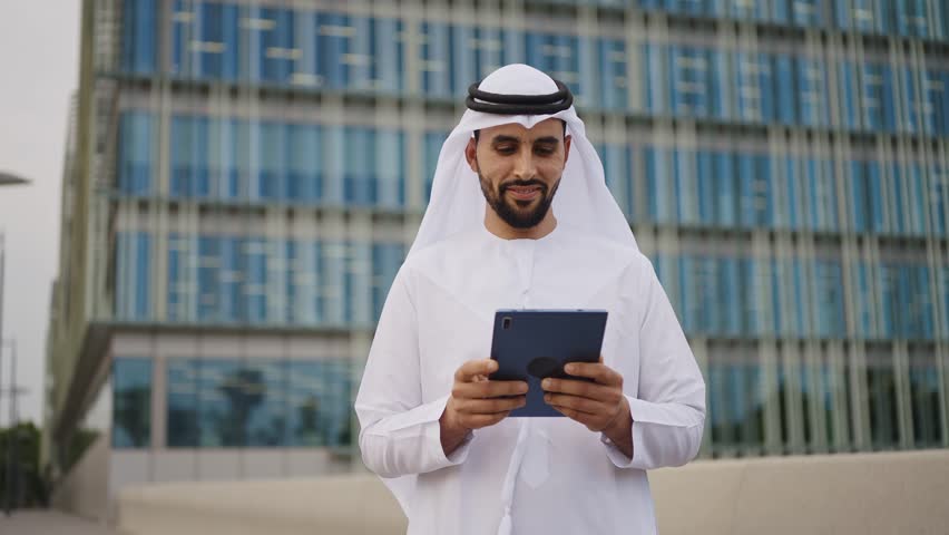 Handsome businessman with the traditional emirates white outfit working outdoor in Dubai city. Concept about middle eastern cultures and business Royalty-Free Stock Footage #1106372523