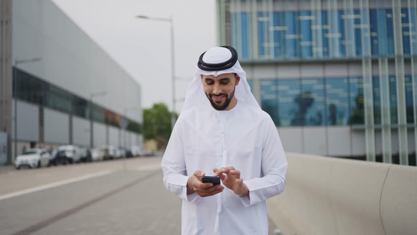 Handsome businessman with the traditional emirates white outfit working outdoor in Dubai city. Concept about middle eastern cultures and business Royalty-Free Stock Footage #1106372529