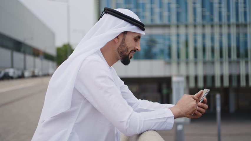 Handsome businessman with the traditional emirates white outfit working outdoor in Dubai city. Concept about middle eastern cultures and business Royalty-Free Stock Footage #1106372537
