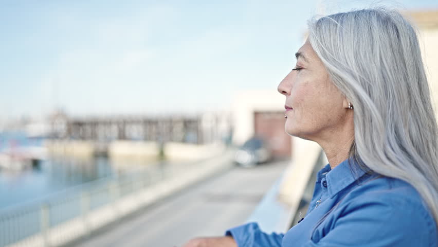 Middle age grey-haired woman smiling confident standing at seaside