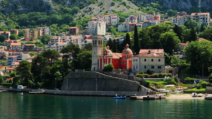 View from sea to shore with old town and nature. Church close-up. Trucking right shot. Summer in Montenegro