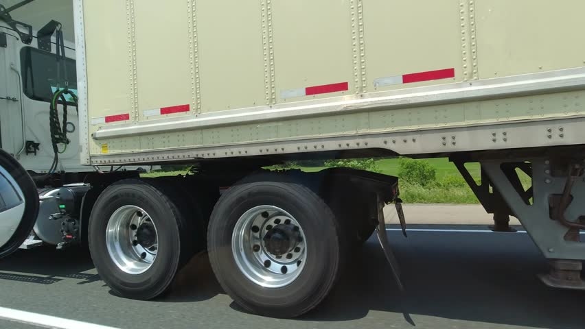 Close up of cargo truck wheels and tires. Passing semi truck on highway. Freight heavy duty vehicle. Canadian commercial industrial tracking, transportation and delivery. Royalty-Free Stock Footage #1106378883