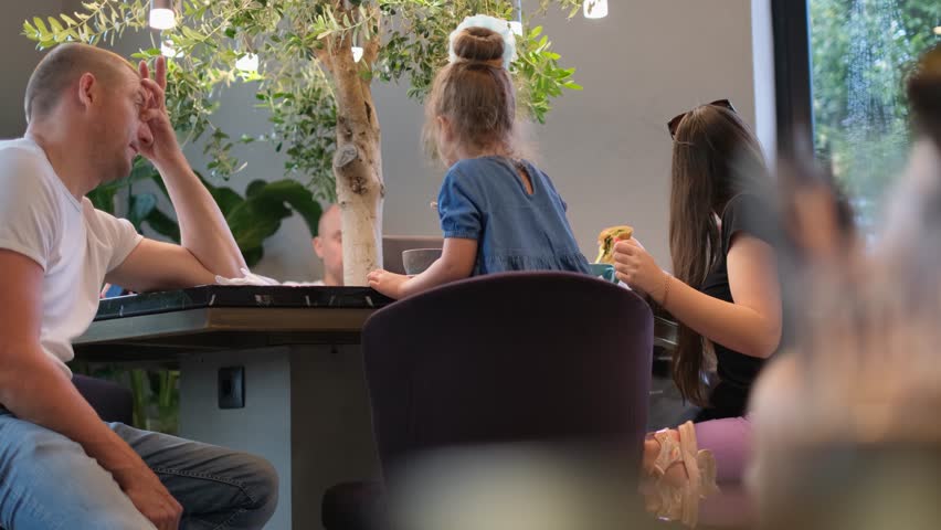 Young family: parents and little daughter having lunch and drinking coffee