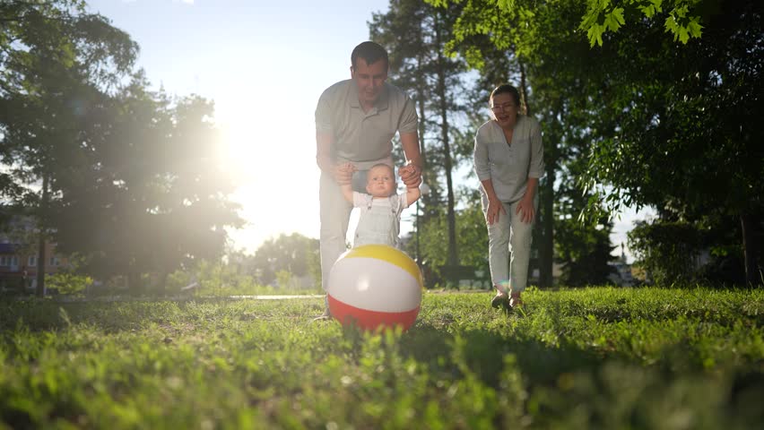 happy family in the park. mom dad and baby play ball at sunset in the park. happy family a kid dream concept. baby toddler plays ball with nature parents at sunset. people in fun park