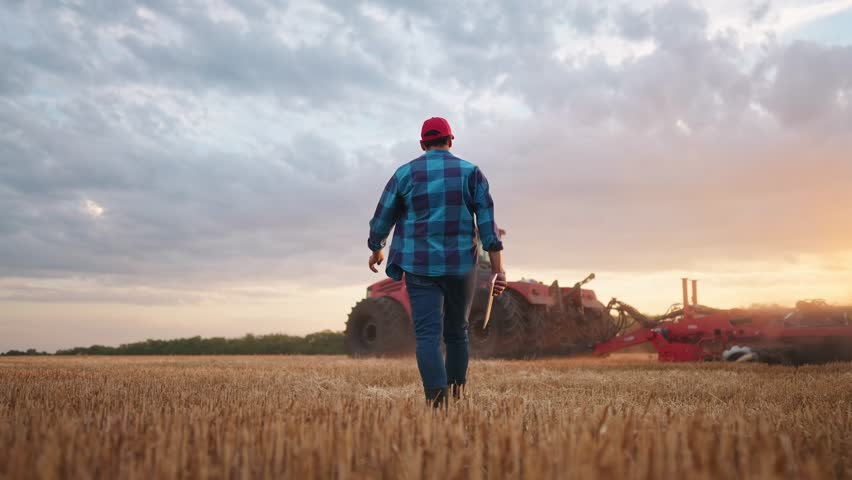 agriculture. farmer walk works in a field next to a tractor that plows the land. business agriculture concept. farmer with tablet works in field next to a tractor at farm sunset mowed wheat plows Royalty-Free Stock Footage #1106381687