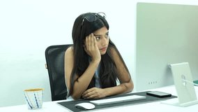 Shot of an Indian Girl having headache while working on a Computer in office
