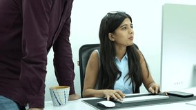 A Shot of an Indian Girl having work discussions while working on her Computer in office

