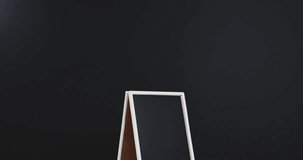 Video of blackboard sign on white stand with copy space on black background. Signage and writing space concept.