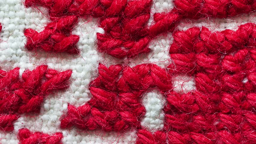 Video of handmade red and white cross-stitch floral ornament of red roses on white linen tablecloth. Needlework and DIY concept. Top view, macro, flat lay, mockup, close-up