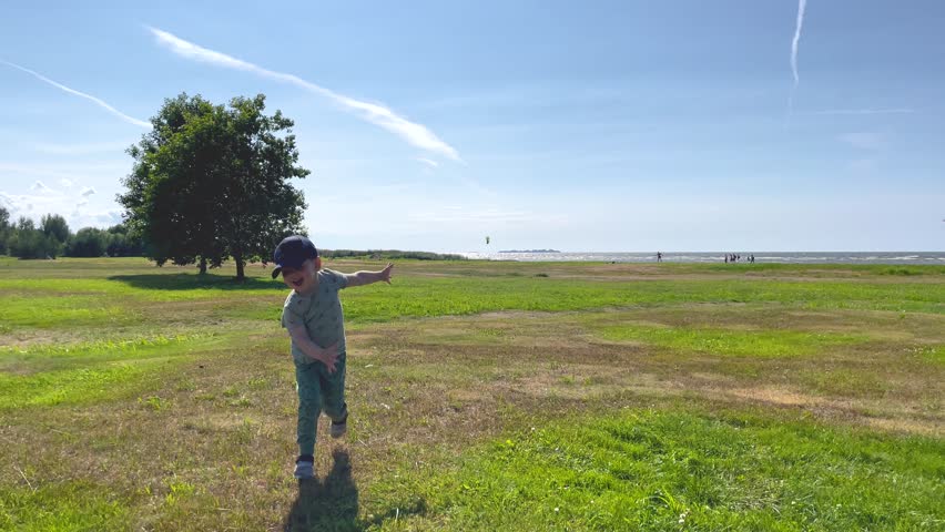 Kid. A little happy kid is spinning around himself, arms outstretched. The child walks in nature. A clearing, a sunny summer day. The seashore.