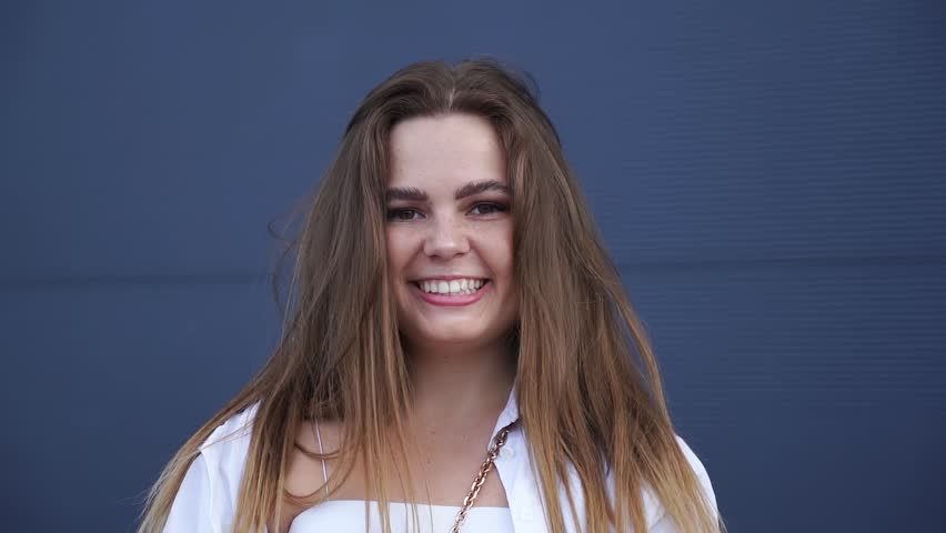 Portrait of young Caucasian girl in white shirt posing for camera. Close-up