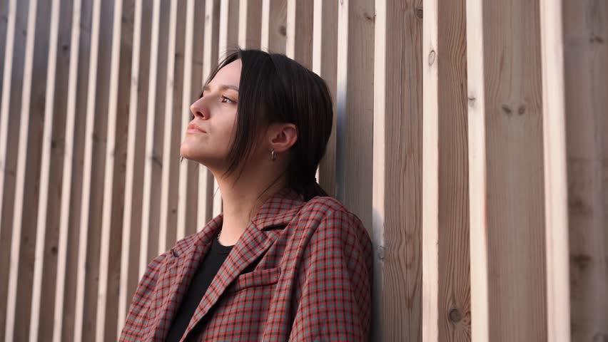 Portrait Young attractive girl model poses for camera on a wooden background. city