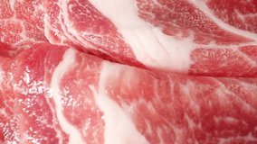 Macro video captures the intricate details of raw pork neck slices, showcasing the marbling and textures with stunning clarity. reveals a visually captivating exploration of this delicious cut. 4K
