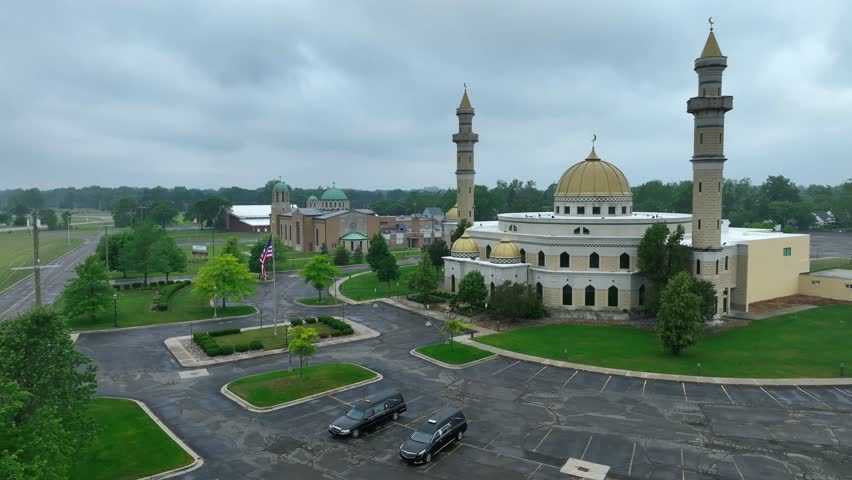 Aerial approaching shot of Islamic Center of American with forest and dense clouds at sky in backdrop - Establishing drone shot