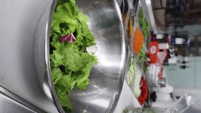 Close vertical video of a cook preparing a salad on a metallic bowl.