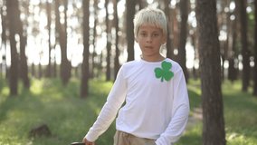 Cute little boy in leprechaun costume posing for a video. Portrait of 10 year old kid wearing high hat with green ribbon and shamrock symbol
