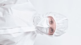 Vertical video. Environmental danger. Water contamination. Cholera infection. Confident woman scientist in protective coverall suit mask goggles isolated on grey background.