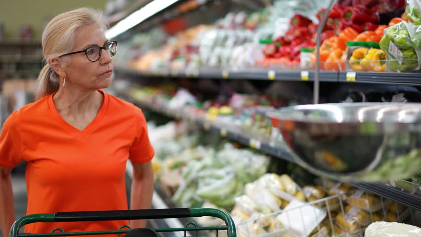 Closeup of a happy pretty mature woman pushing a shopping cart in a grocery store. - Powered by Shutterstock - Get 15% off with code: PIKWIZARD15