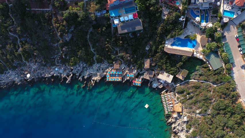 Summer hotels with swimming pools and sea views lined up side by side on a steep rocky slope at Kas, Cukurbag Peninsula in Turkey. Boutique hotels overlooking the Mediterranean Sea. Bird