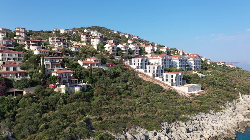 Summer houses with sea view and swimming pool clustered on a hill in Cukurbag Peninsula in Kas, Turkey. White houses and hotels overlooking the Mediterranean Sea
