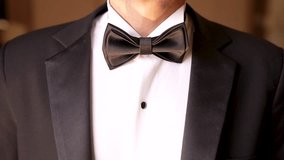The groom in the black suit adjusts his bow tie of the white shirt - close up - Powered by Shutterstock - Get 15% off with code: PIKWIZARD15