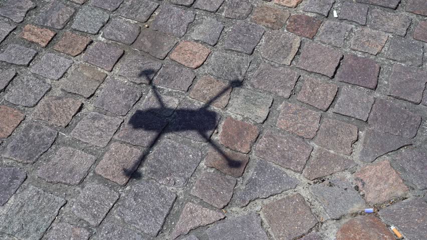 Silhouette shadow of flying drone over paving stone pathway on a hot sunny summer day at Swiss City of Zürich. Movie shot July 20th, 2023, Zurich, Switzerland.
