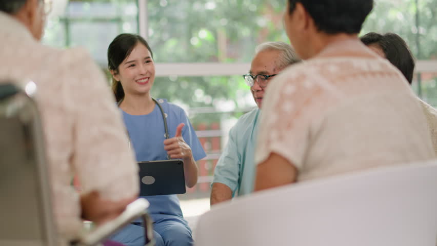Group of asian senior people listening to young nurse.Psychological support group for elderly therapy session in a community centre. Group therapy in session sitting in a circle in a nursing home. Royalty-Free Stock Footage #1106414337