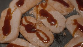 This close up video shows slices of luncheon meat frying on a pan for masubi.
