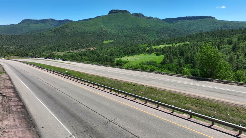 Scenic highway with no traffic. Aerial establishing shot of Colorado freeway with Rocky Mountains in summer.