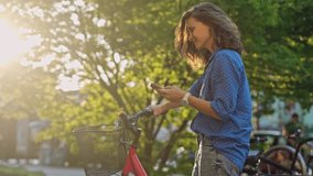 A young Caucasian woman using a phone while standing next to her bicycle in the city street. - Powered by Shutterstock - Get 15% off with code: PIKWIZARD15