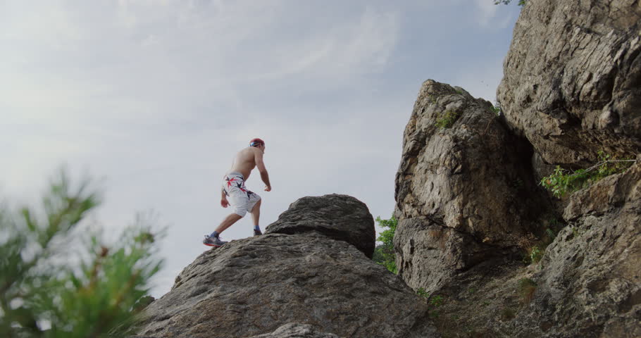 rock climber jumping from ridge to edge, mountain climbing, freeclimbing man, bouldering in rocky environment, adventurous, spectaculair, solo, action shot, static cinematic wide in sunny landscape. Royalty-Free Stock Footage #1106420629