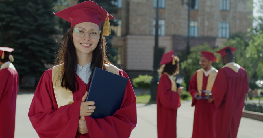 Slow motion portrait of ambitious young lady graduate student standing on campus holding diploma. People and higher education concept. Royalty-Free Stock Footage #1106423969