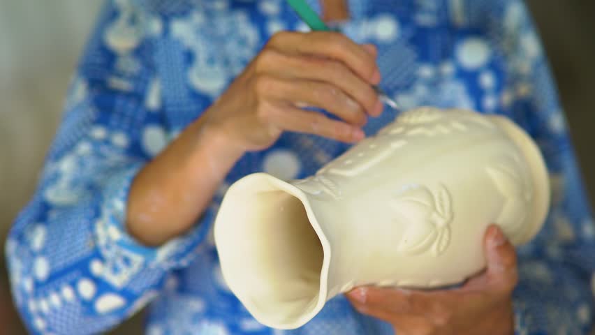 a Vietnamese worker in traditional craft village making pottery and porcelain cups containing rubber tree latex in Tay Ninh, Vietnam. Business and travel concept. Selective focus