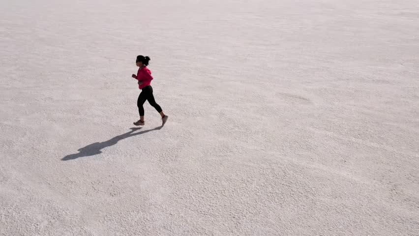 Aerial shot of an Asian woman jogging across the Bonneville Salt Flats flats in Utah