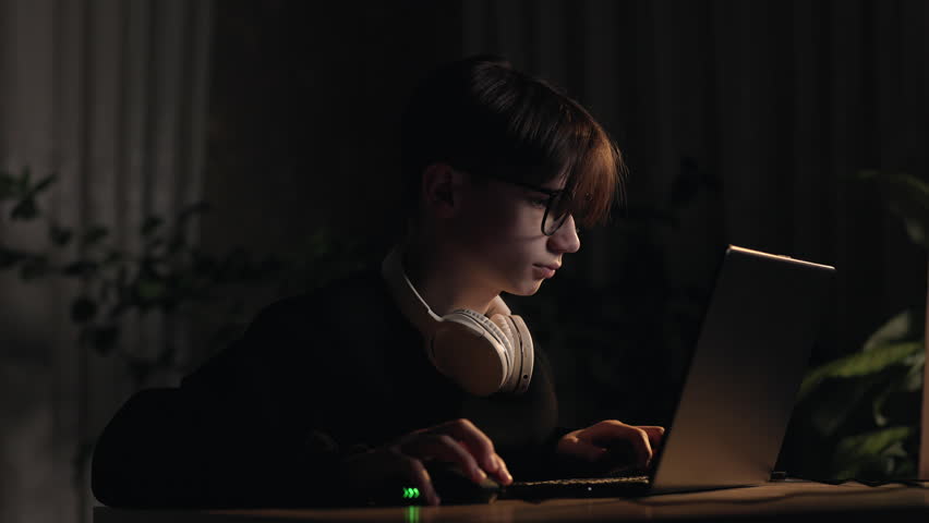 Video games gambling addiction. Concentrated teen boy plays a computer shooter video game, esport, virtual competition on mouse with keyboard at dark home room. Online video game technology concept Royalty-Free Stock Footage #1106430345
