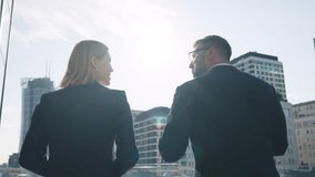 Back view following two business partners man woman walking along terrace office building roof overlooking modern city skyscrapers, discuss work exchanging smiles and positive vibes in sunshine rays - Powered by Shutterstock - Get 15% off with code: PIKWIZARD15