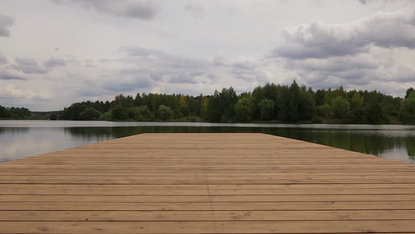 Man comes to edge of pier and enjoys view of lake or river