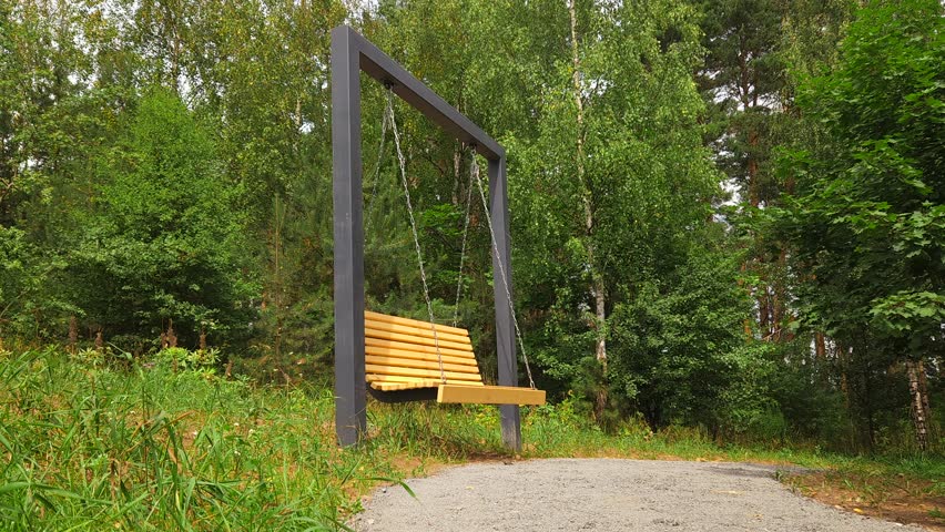 Middle-aged man resting on swing in city park