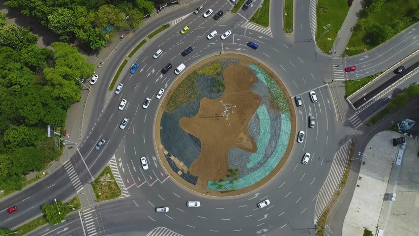 4K Aerial Drone Footage of a busy city roundabout intersection. Cars driving on multiple lane roads merging and going around. Royalty-Free Stock Footage #1106439705