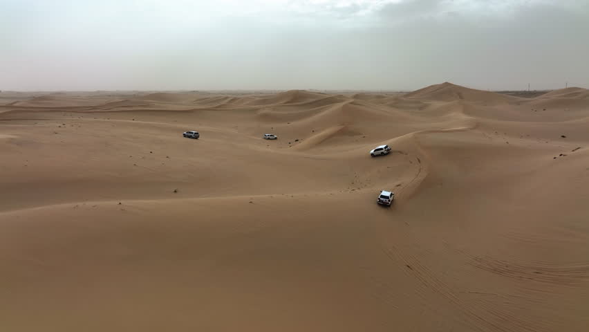 Aerial view of 4x4 off road trucks driving over dunes of the Dubai Desert, in UAE