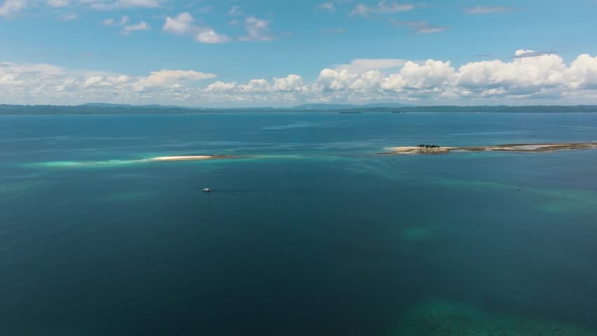 Aerial drone view of Hagonoy Island and Naked Island. Surrounded by deep blue sea under the blue skies. Mindanao, Philippines.