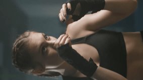 Woman fighter in a combat stance, trains his punches, training in the boxing gym, female trains a series of punches fast, woman power, vertical video.