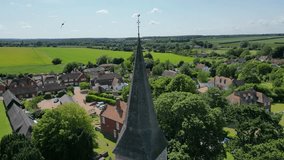 An upward boom-shot of the St John the Evangelist church steeple, rising to unveil the village of Ickham.
