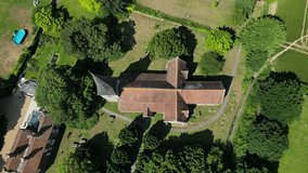 Top-down push-in shot of St John the Evangelist church in Ickham, Kent, with the graveyard in view.