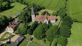 An aerial push-out shot of St John the Evangelist church in Ickham, Kent, with parts of the village visible as the camera zooms out.