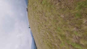 Vertical video 4k. Mountain autumn ridge near sightseeing observation tower at hilly terrain road trail. FPV drone low dynamic shot extreme sport motorcycle travel parking chilling rocky cloudy sky