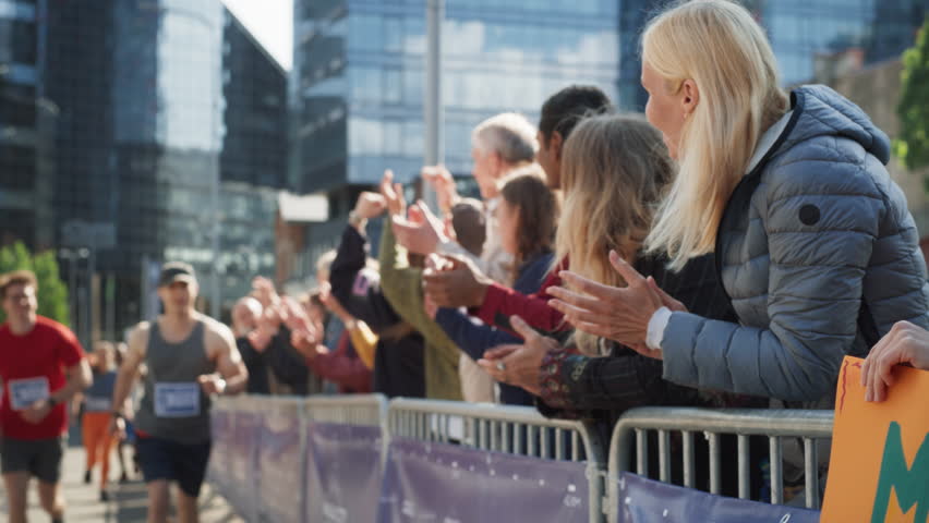 Marathon Audience Supporting and Cheering Their Loved Ones Participating in the Race: Athletic Male Marathon Runner Giving a High Five to Female Family Member in the Audience While Running Royalty-Free Stock Footage #1106455949