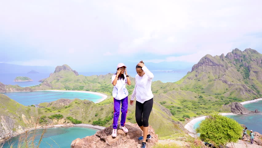 Teenager enjoying view of Padar Island, labuan bajo while standing in rock. Tropical Island Landscape.