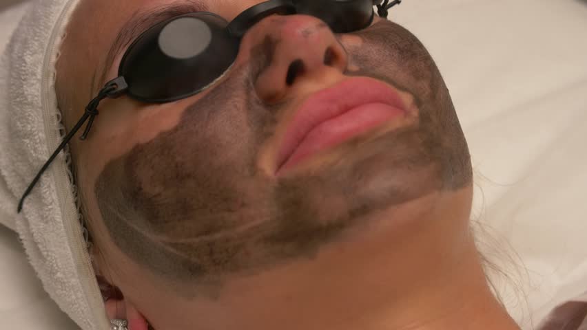 Facial cleansing procedure with carbon peeling in a spa salon. Close up top view.